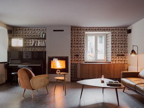 Cozy living room with wood-paneled walls, fireplace, piano, and mid-century modern furniture.