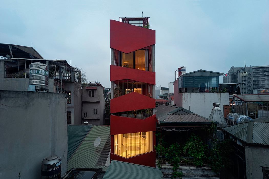 A modern, red-colored high-rise building with unique architectural design features.