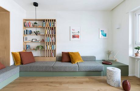 Bright, modern living room with built-in bookshelves, gray sofa, and colorful accents.