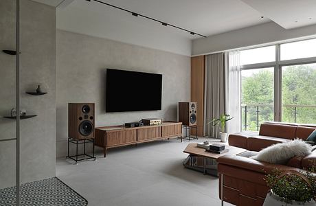 Minimalist living room with a large TV, wooden media console, and sleek audio system.