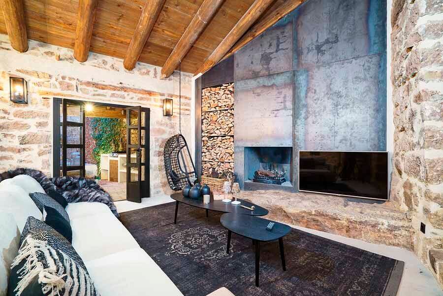 Rustic, cozy living room with exposed stone walls, wood beam ceiling, and modern furnishings.