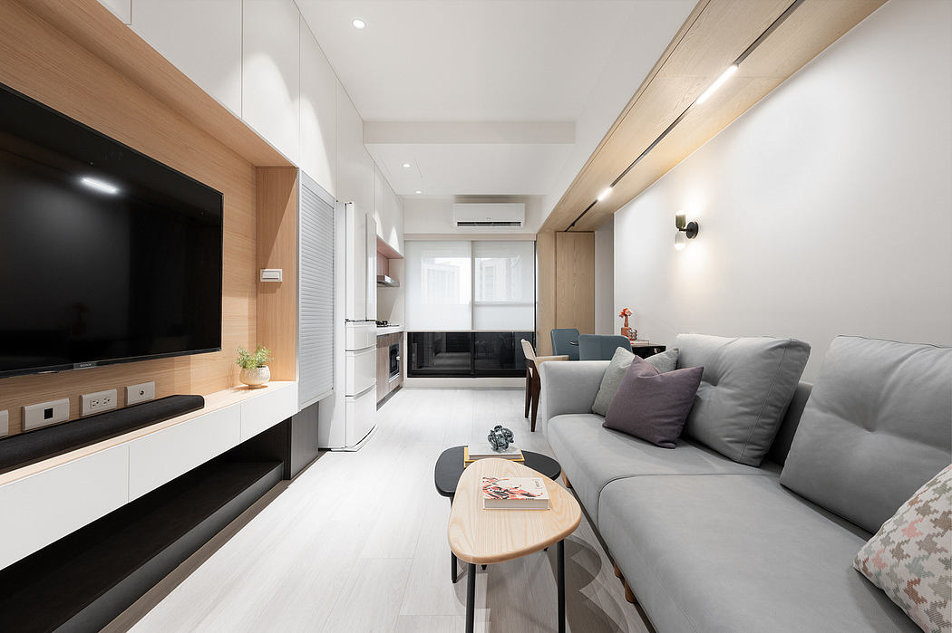 Minimalist living space with wood and white tones, modern furniture, and built-in television.