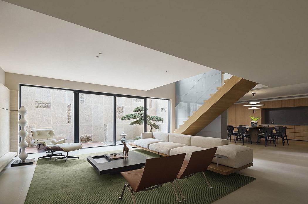 Spacious modern living room with large windows, sleek furnishings, and a bonsai tree.