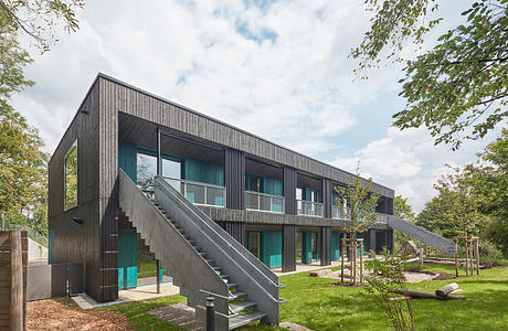 Sleek, dark wooden exterior with striking geometric patterns and large windows against green landscape.