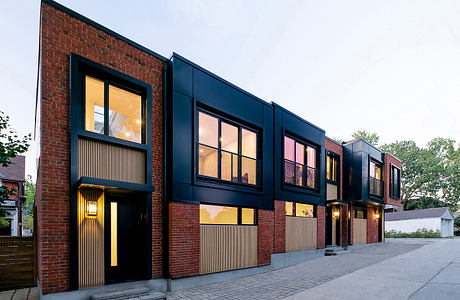 A modern brick and glass building with clean lines and warm interior lighting.