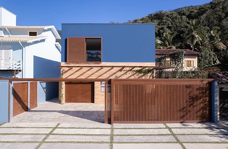 Modern single-family home with wood accents, balconies, and a lush tropical backdrop.