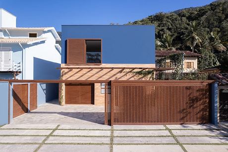 Modern single-family home with wood accents, balconies, and a lush tropical backdrop.