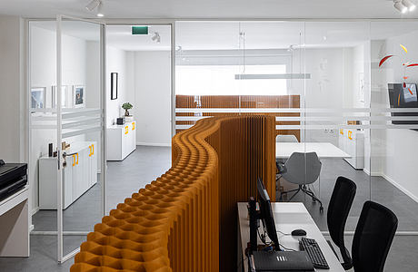 A modern, minimalist office design with geometric wood paneling and sleek white furniture.