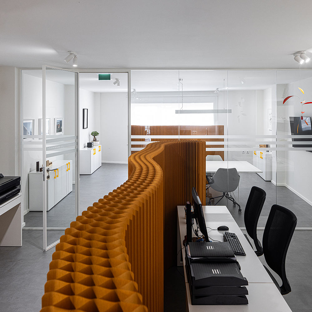 A modern, minimalist office design with geometric wood paneling and sleek white furniture.