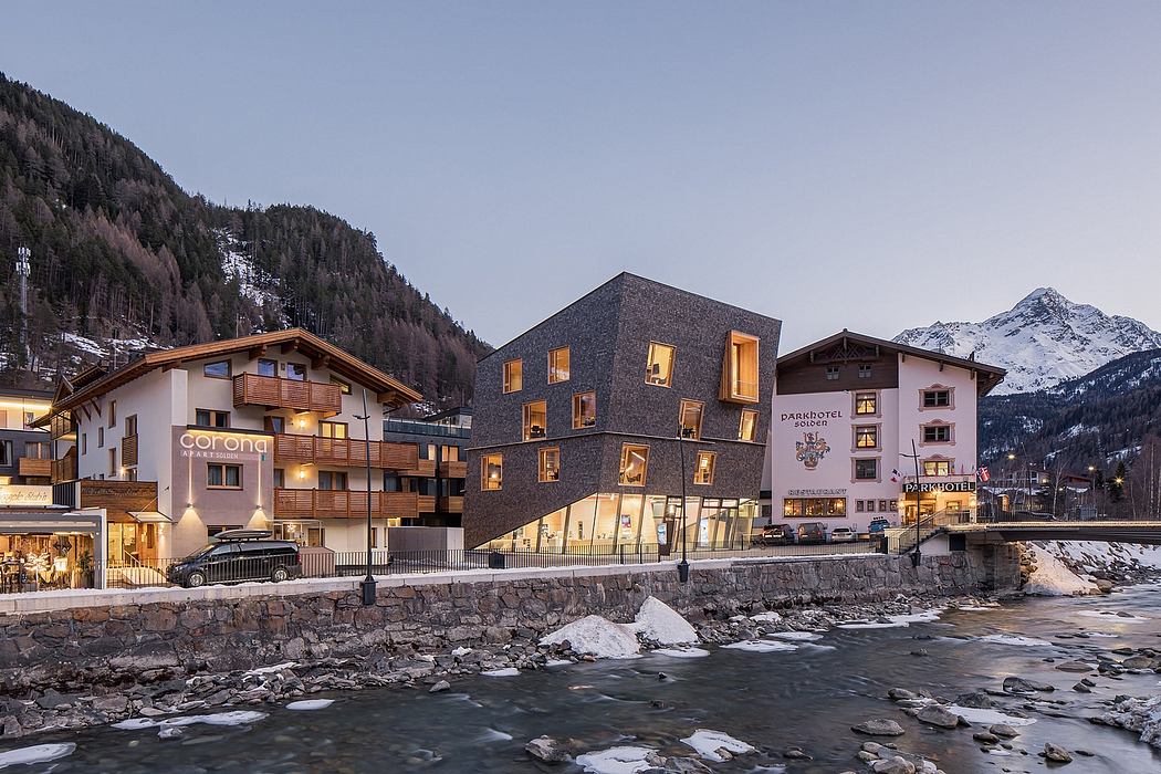 Modern, alpine-inspired architecture with wooden accents, set against snowy mountains.