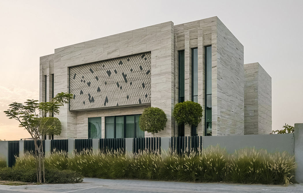 A modern, monumental concrete building with intricate facade patterns and landscaped surroundings.