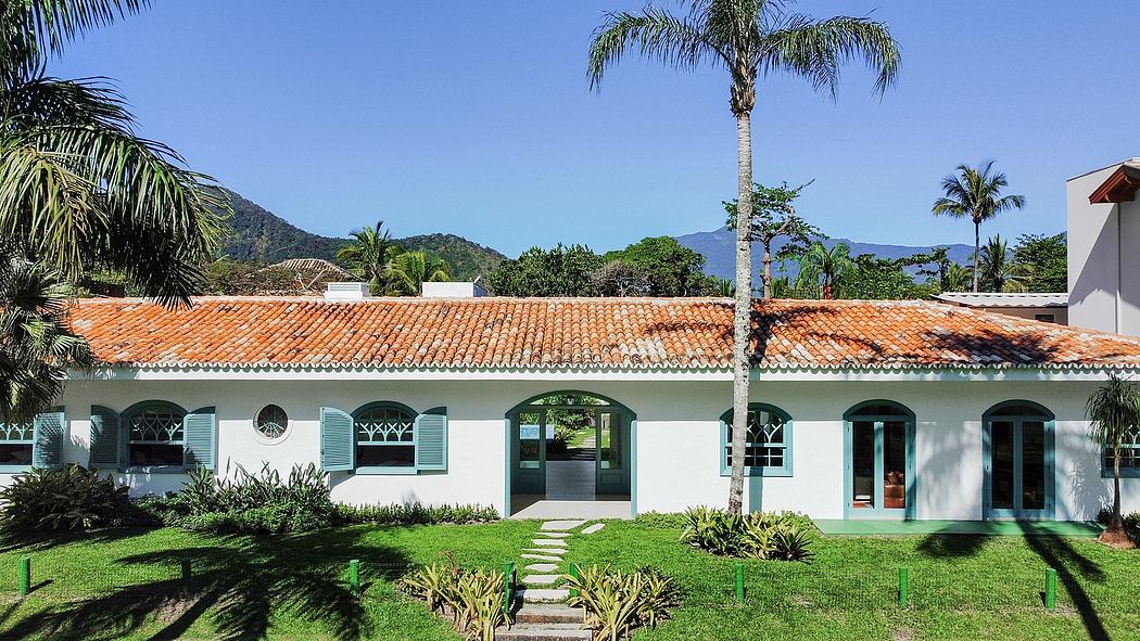 A peaceful, tropical-inspired villa with tiled roof, arched windows, and lush greenery.