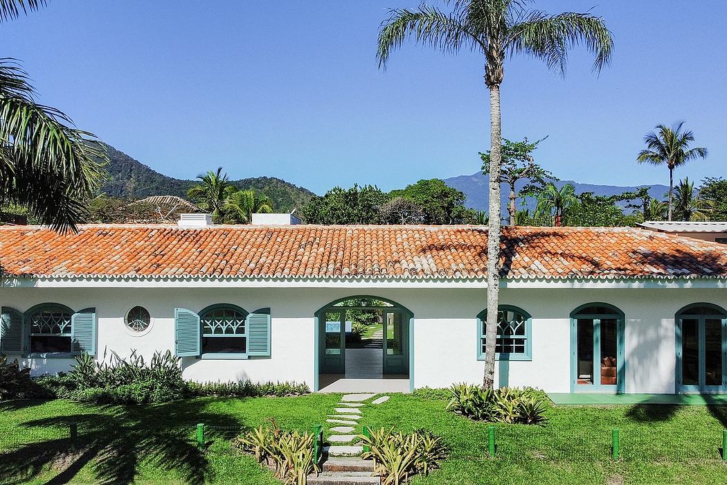 A peaceful, tropical-inspired villa with tiled roof, arched windows, and lush greenery.