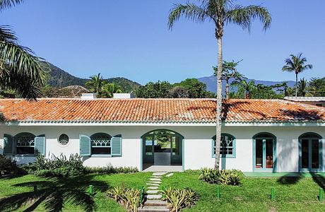 A peaceful, tropical-inspired villa with tiled roof, arched windows, and lush greenery.