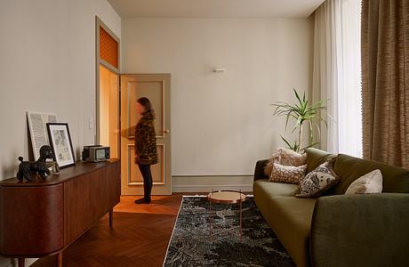 Cozy living room with mid-century furnishings, textured curtains, and potted plant.