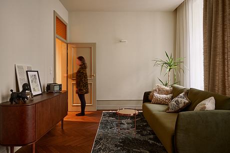 Cozy living room with mid-century furnishings, textured curtains, and potted plant.