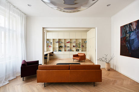 Minimalist living room with built-in shelves, leather furniture, and herringbone flooring.