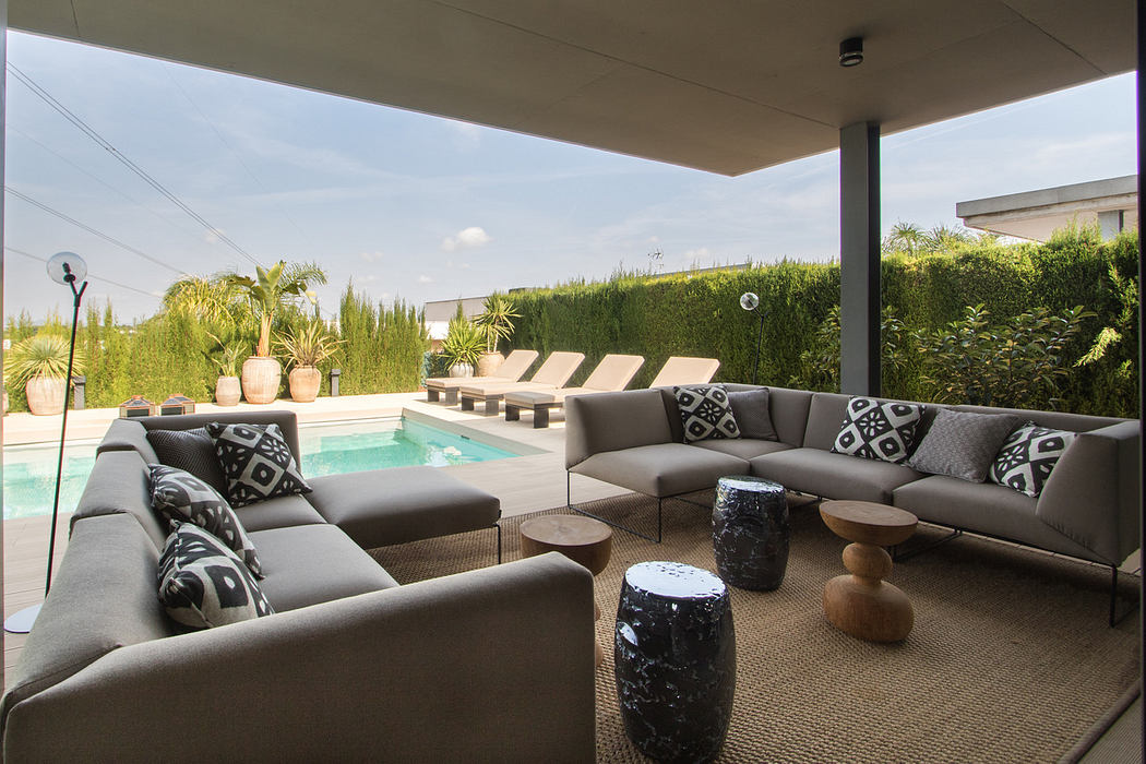 Sleek, modern outdoor living space with L-shaped couch, coffee tables, and pool.