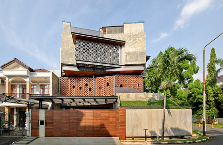 Modern architectural design with intriguing brick pattern and wooden accents, surrounded by lush greenery.