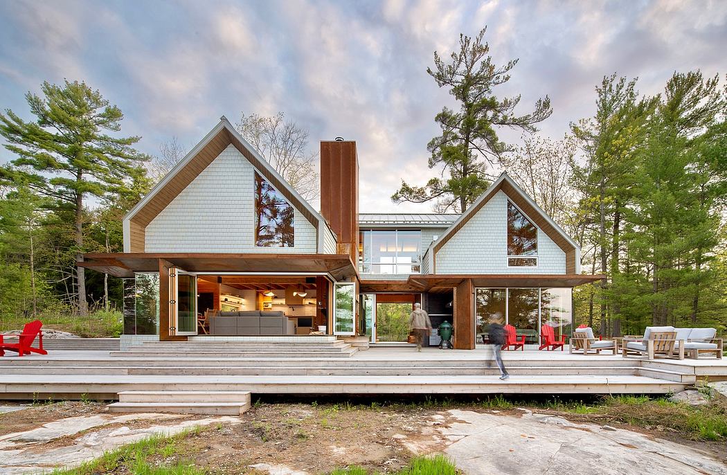 Modern lakeside home with gable roofs, wooden accents, and expansive porch.