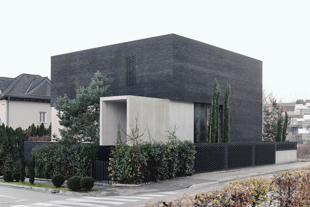 Striking modern building with dark brick exterior, minimal design elements, and surrounding greenery.