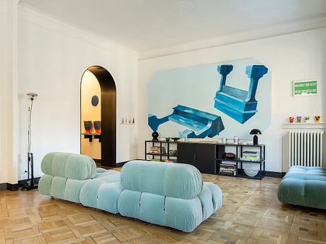 A vibrant, retro-inspired living room with plush mint-colored furniture and modern art.