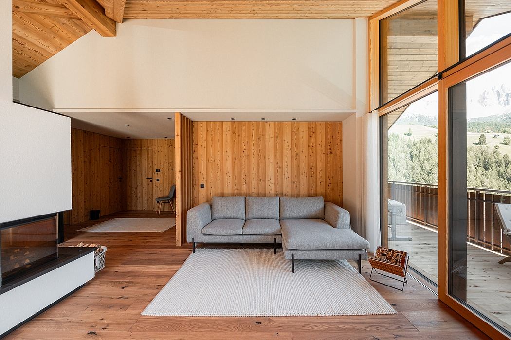 Rustic wooden cabin interior with modern minimalist furnishings and large windows overlooking forested landscape.