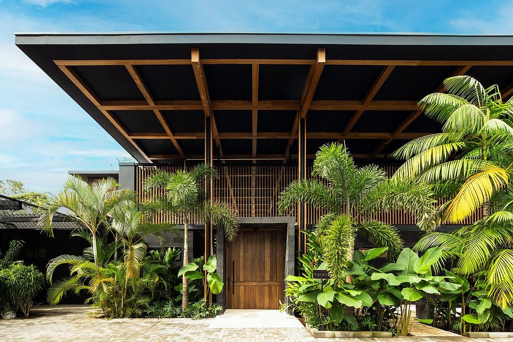 Tropical-inspired wooden pavilion with lush greenery and a grand entrance.
