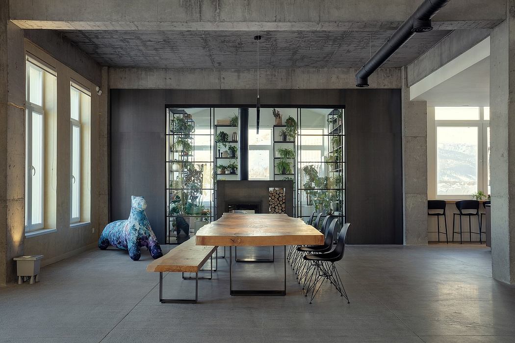 Industrial-style dining area with wooden table, bench, and plants in concrete space.