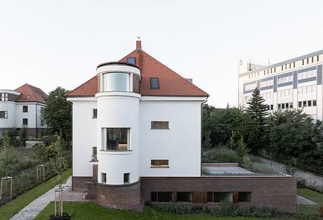 A distinctive residential building with a curved facade, prominent roof, and mix of brick and white elements.