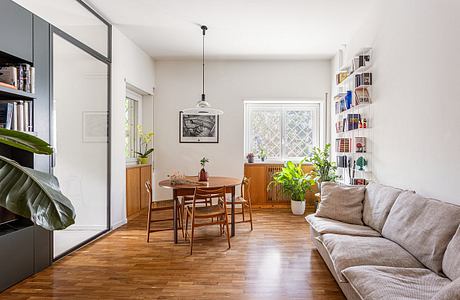 Cozy living room with wooden dining table, shelving, and large window with intricate lattice design.