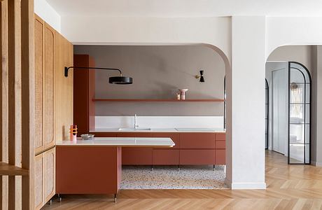 Sleek, minimalist kitchen with warm wood accents, terrazzo flooring, and arched alcove.