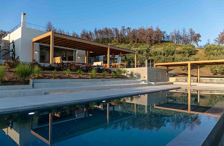 Modern outdoor terrace with covered seating area, reflecting pool, and lush landscaping.