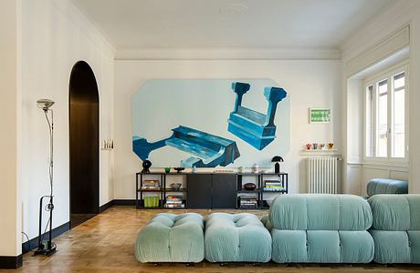 Stylish contemporary living room with vibrant teal sofa, shelving, and bold artwork.