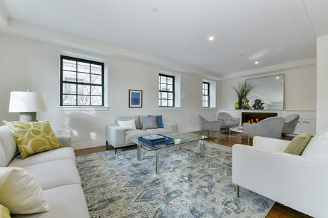 Spacious living room with large windows, plush seating, and a glass-top coffee table.