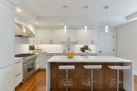 Sleek, modern kitchen with clean white cabinets, wood-accented island, and pendant lighting.