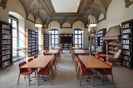 A magnificent library with vaulted ceilings, arched windows, and rows of wooden tables and chairs.