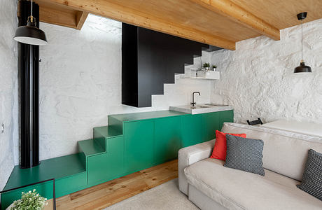 Cozy cabin interior with rustic wood ceiling, modern green cabinetry, and sleek staircases.