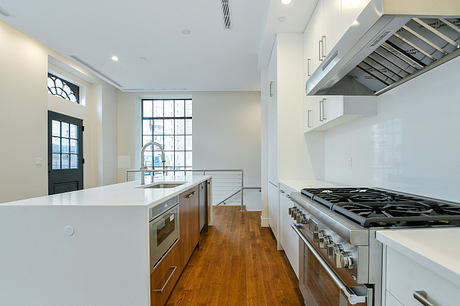 Sleek, modern kitchen with stainless steel appliances, white countertops, and hardwood floors.