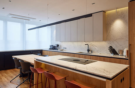 Sleek, modern kitchen with marble countertops, wood cabinetry, and bold pendant lighting.