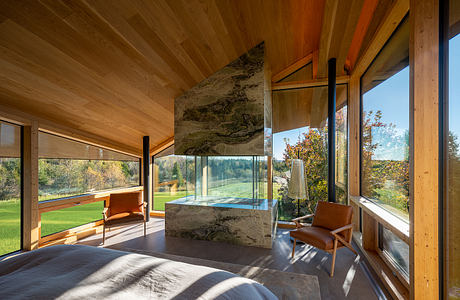 Spacious wooden cabin with a large window overlooking a lush, green landscape.