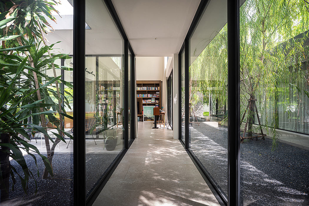 Minimalist hallway with lush greenery visible through large windows and glass doors.