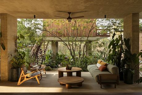 Cozy covered patio with lush greenery, wooden furniture, and a ceiling fan creating a serene ambiance.