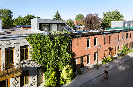 A modern structure with glass panels stands atop a row of historic brick buildings, complementing the urban landscape.