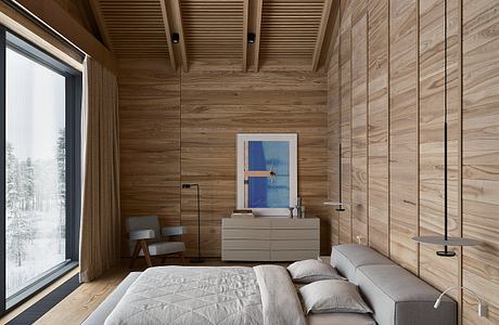 A cozy, wood-paneled bedroom with a large window overlooking a snowy landscape.