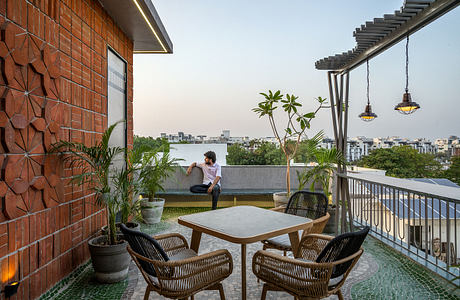 Modern rooftop terrace with brick walls, potted plants, outdoor furniture, and city view.