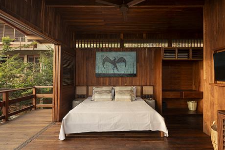 Rustic wooden cabin interior with large framed artwork, cozy bed, and access to outdoor balcony.