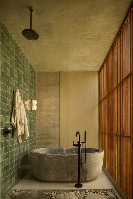 The image depicts a minimalist bathroom with a stone tub, wooden paneling, and a suspended showerhead.