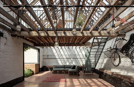 A rustic industrial loft with exposed wooden beams, metal staircase, and cozy seating.