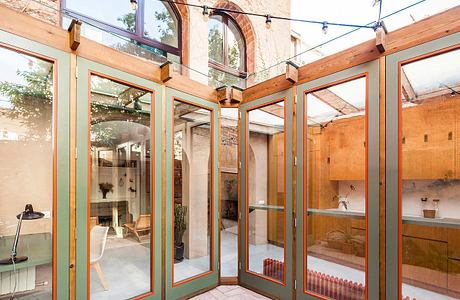 Arched brick facade with wood-framed windows and interior shelving and decor.